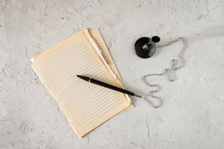 Writing pen on a chain and old yellowed sheets of paper on a gray concrete backgroundの写真素材