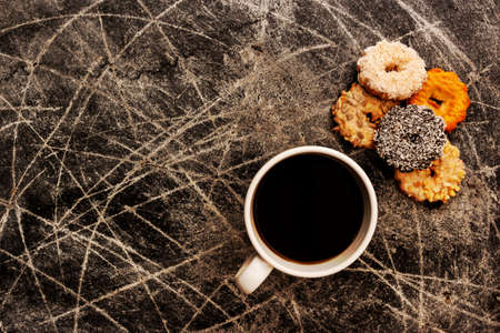 Coffee in a white cup and cookies of different colors and tastes on a dark scratched backgroundの写真素材