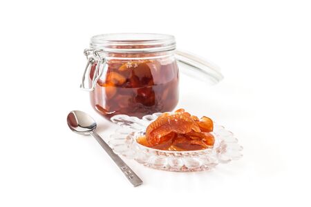 Jam from apple slices in a glass jar close-up and a socket with jam isolated on a white backgroundの写真素材