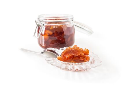 Jam from apple slices in a glass jar close-up and a socket with jam isolated on a white backgroundの写真素材