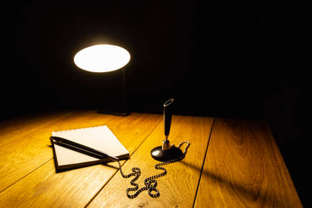 Notepad and pen on a wooden table in the light of a table lampの写真素材