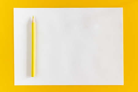 Yellow pencil and blank sheet of white paper on a yellow backgroundの写真素材