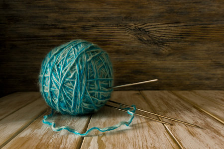Ball of two-tone wool and knitting needles on old painted wooden backgroundの写真素材