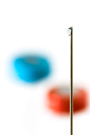 Medical needle with a drop of vaccine against the background of vaccine vialsの写真素材