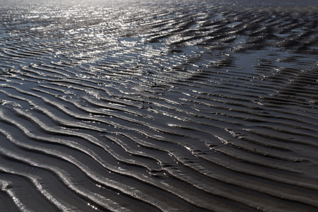 Wet wavy sand on beach in Sankt Peter-Ording in northern Germanyの写真素材