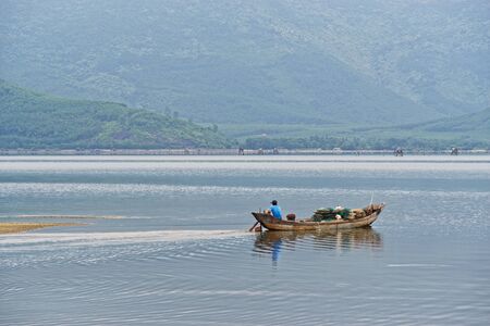 Small fishing boat floating on the lake against mountains. Lang Co, Vietnamの写真素材