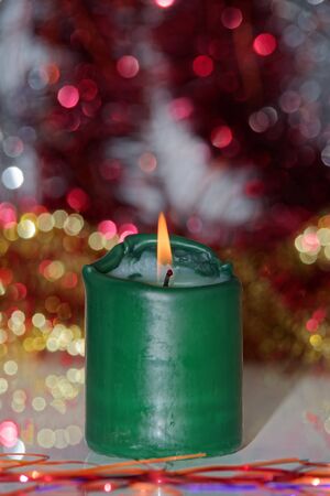 Single green burning candle against blurred background. Focus on the flameの写真素材