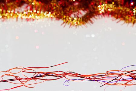 Christmas decoration from red and yellow tinsel on white surface with copy spaceの写真素材