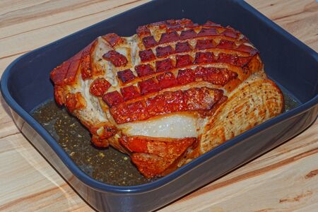 Roast pork with crackling in the baking dish on wooden backgroundの写真素材