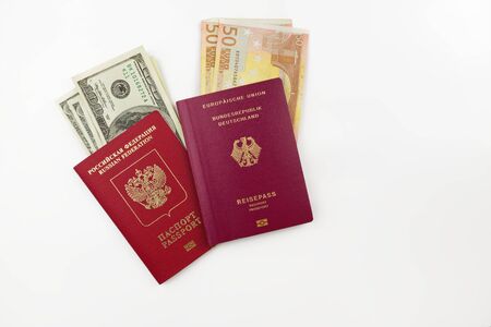Official German and Russian passports with american dollars an euro banknotes on white backgroundの写真素材
