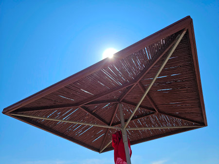 Low angle view of wooden parasol against clear blue sky on sunny dayの写真素材