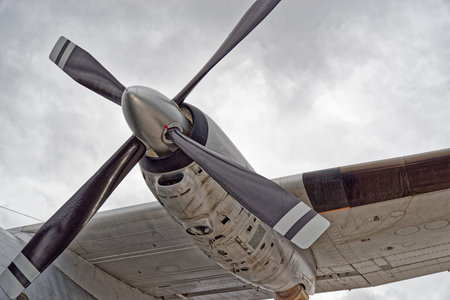 Detailed view of aircraft propeller blade against dramatic cloudy sky, showing aviation engineering....