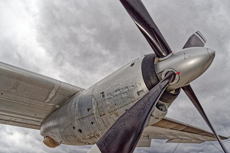 Detailed side view of aircraft propeller blade against dramatic cloudy sky, showing aviation...