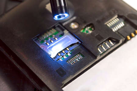 Small usb endoscope shines on the inside of a broken phoneの写真素材
