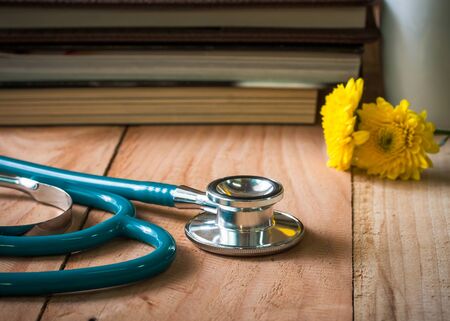 stethoscope and yellow flower on wooden table.の写真素材
