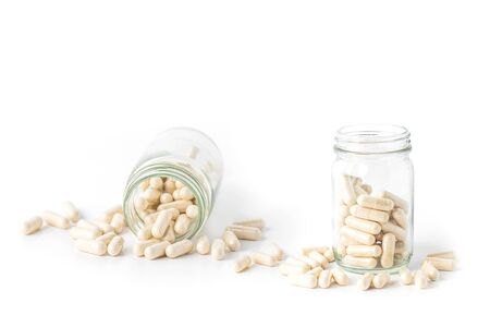 herb capsule pills spilling out off bottle isolated on white background.Image for Medical Concept.の写真素材