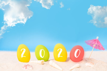 2020 text on colorful eggs on white sand beach over blue sea,happy Happy new year 2020  or Easter...