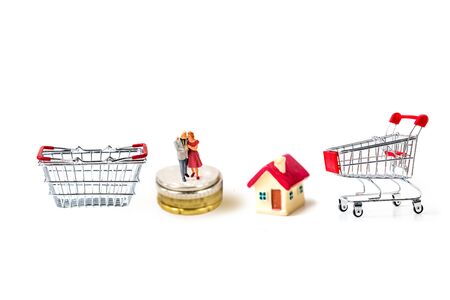 miniature older couple family wear Christmas cap stand on stack coins with tiny home isolate on white background,  Image for Christmas and holiday home and money  management concept.の写真素材