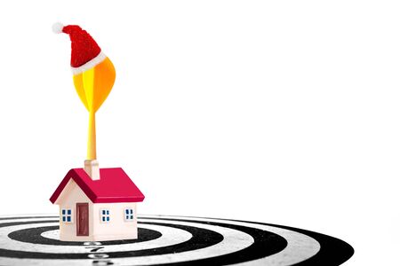 target dart with arrow and Christmas cap with miniature home isolated on white background ,image for Christmas holiday target marketing concept .の写真素材