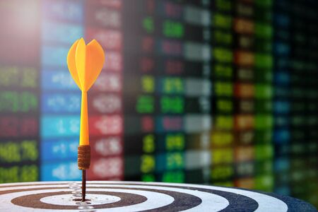 target dart with arrow over blurred stock share chart with indicator of candle bar up and down trend and over blur background,image for target marketing concept.の写真素材