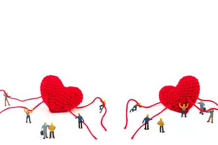 miniature worker holding robe heart shape on white backgroundの写真素材