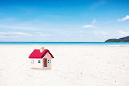 miniature house with red roof on tropical sand beach over blurred clear sky on day noon light.Image for property real estate investment concept.の写真素材