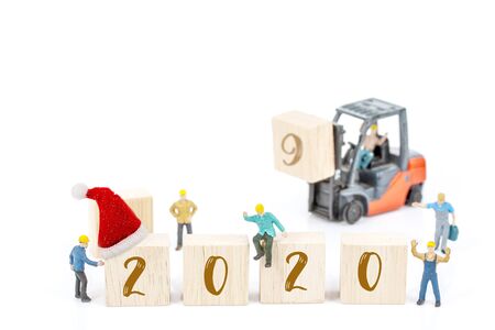 miniature worker team building standing front of forklift machine with white 2020 number on wooden block on white background, decoration to Happy new year 2020 concept.の写真素材
