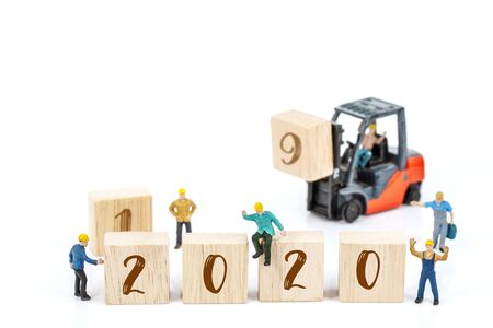miniature worker team building standing front of forklift machine with white 2020 number on wooden block on white background, decoration to Happy new year 2020 concept.の写真素材