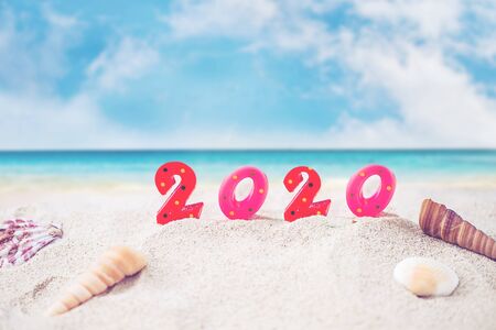 Colorful Candle Number 2020 Over Blurred Blue Sea and Sand Beach with Clear Blue Sky ,Image for New Year 2020 Celebration Decorative Concept.の写真素材