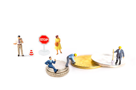 Miniature people : Businessman and business woman standing on coins with stop sign.の写真素材