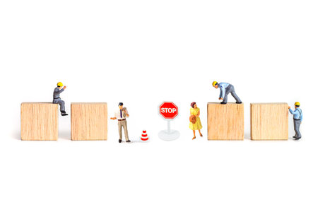 Miniature people : Engineer, architect, construction worker standing on wooden block with stop sign.の写真素材