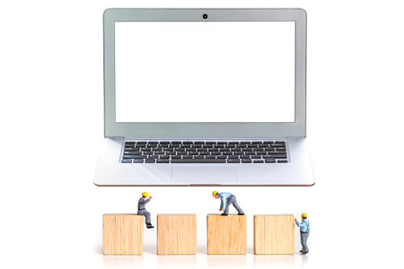Miniature people : Worker assembling wooden block with laptop computer isolated on white backgroundの写真素材