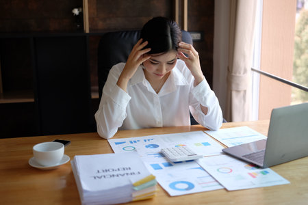 Stressed businesswoman sitting at her desk in office, she is stressed and worried.の写真素材