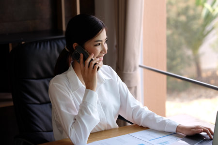 Asian businesswoman talking on the phone while working at her office.の写真素材