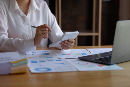 Businesswoman analyzing investment charts with laptop and calculator. Accounting concept.の写真素材