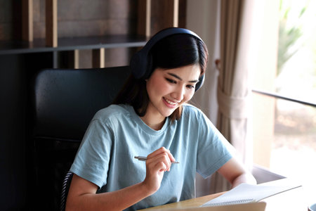 Happy young asian businesswoman listening to music while working in officeの写真素材
