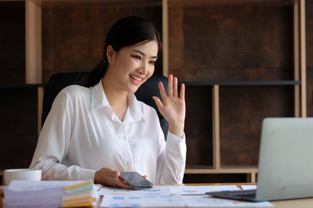 Beautiful asian businesswoman using smart phone and laptop computer in office.の写真素材
