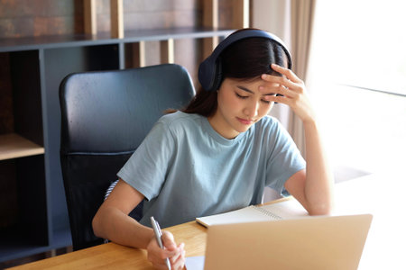 Young asian woman listening to music with headphones and using laptop.の写真素材