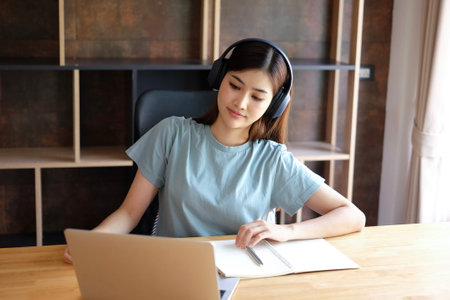 Young asian woman working at home with laptop computer and headphone.の写真素材