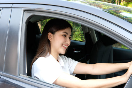 Portrait of a beautiful young asian woman driving a car.