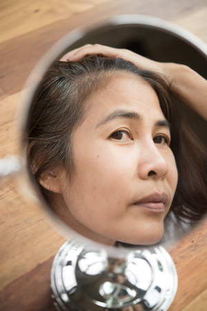 woman looking at her hair for gray hair problemの写真素材