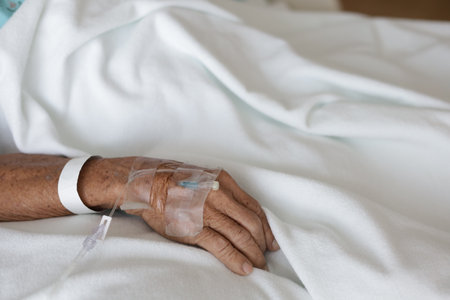 Close-up of senior woman patient lying on bed in hospital wardの写真素材