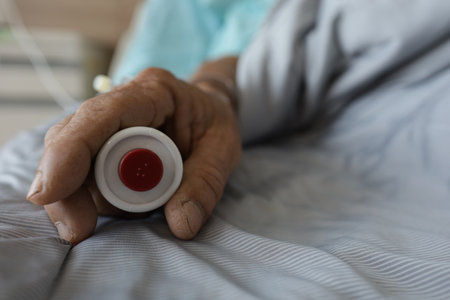 Close up of senior woman hand holding medicine bottle on bed at homeの写真素材
