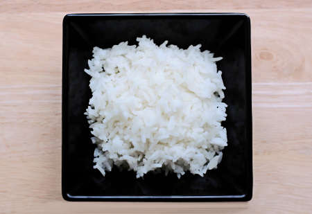 Rice in black plate on wooden tableの写真素材