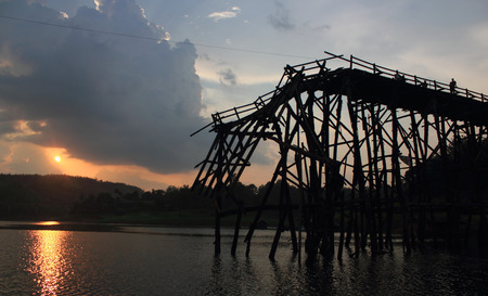 Kanchanaburi- April 26 :  tourist is on old bridge and the sunlight fall with a mountain background at Sangklaburi on April 26, 2014 Kanchanaburi Thailand.のeditorial素材