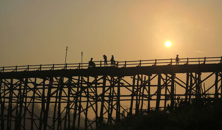 Kanchanaburi- April 26 :  tourist is on old bridge and the sunlight fall with a mountain background at Sangklaburi on April 26, 2014 Kanchanaburi Thailand.のeditorial素材