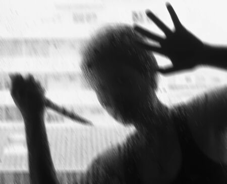 Shadowy figure with a knife behind glass,soft focusの写真素材