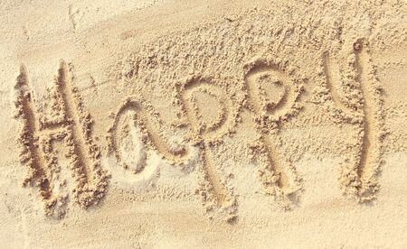 Happy - sand writing on the beachの写真素材