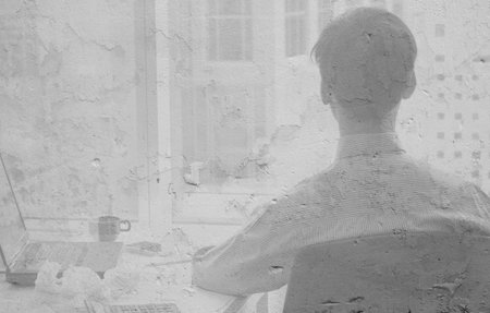 concept, shadow on the wall of a man sitting at his desk and working on his laptopの写真素材