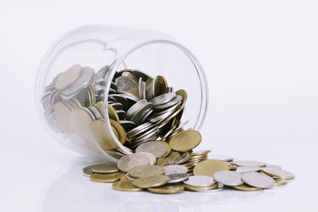 Coins spilling out of a glass bottleの写真素材